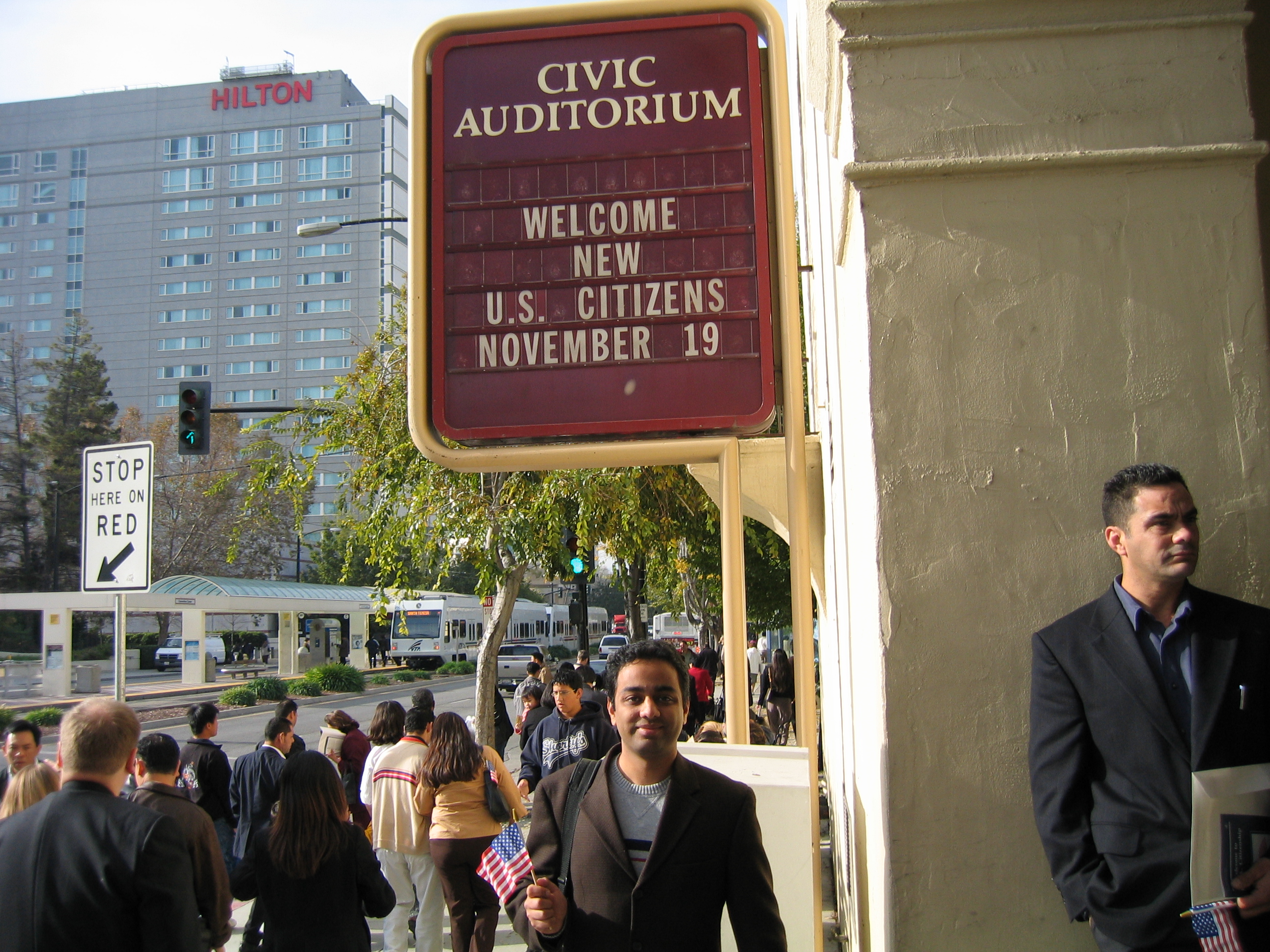 Rajiv standing under the "Welcome New U.S. Citizens November 19" marquee at the Civic Auditorium